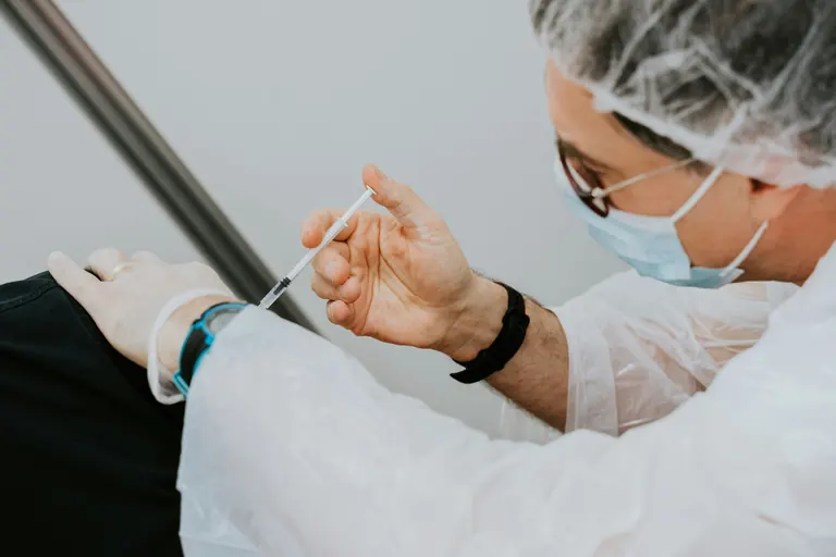 Gloved hands working during a facial procedure in a clinical setting with sterile drapes
