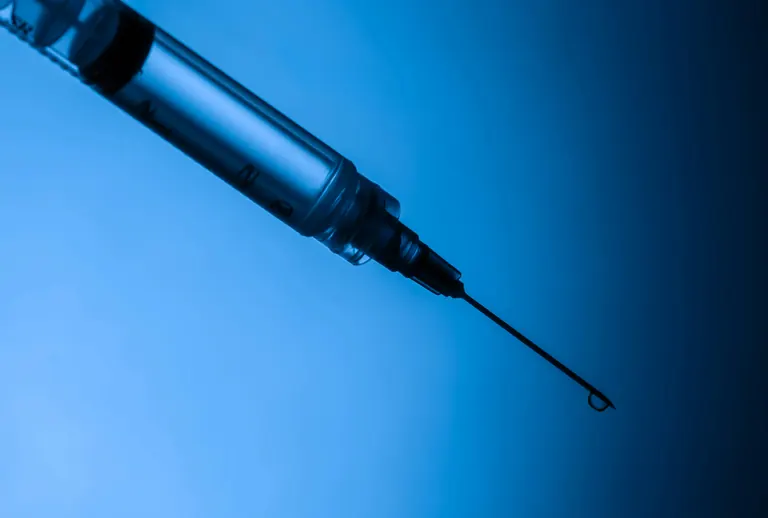 A syringe photographed against a deep blue background