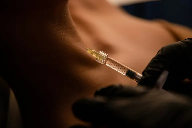 An injection being placed into the skin of a patient’s neck and lower jawline