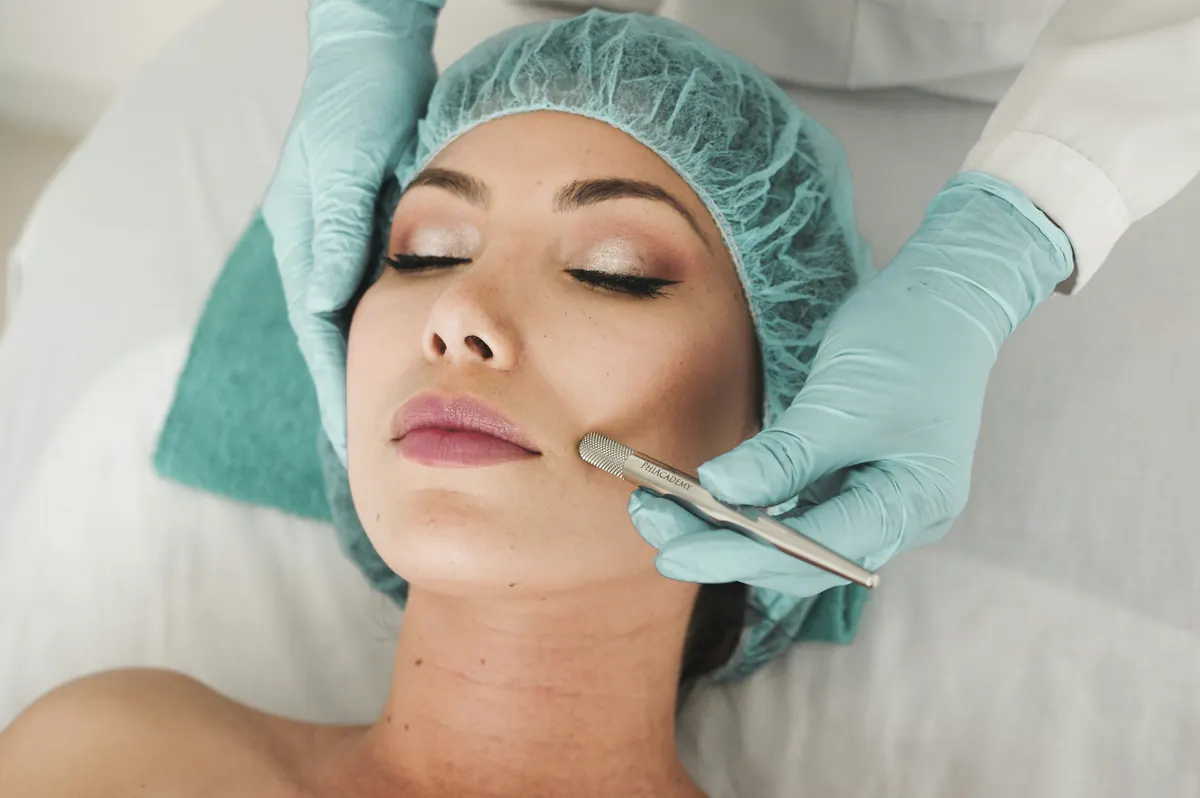 A patient’s face marked with surgical planning lines along the jaw and cheek, with a gloved hand holding an instrument alongside