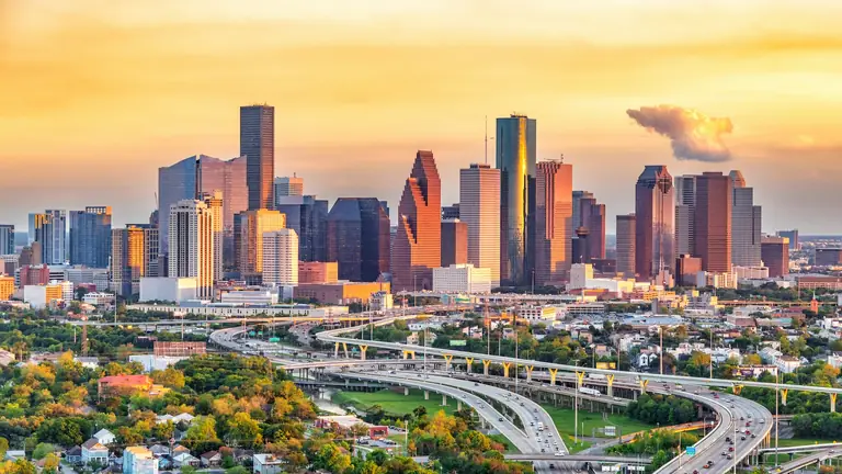 The downtown Houston, TX skyline at sunset above the freeway interchange